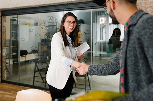 a woman and a man shake hands across a desk