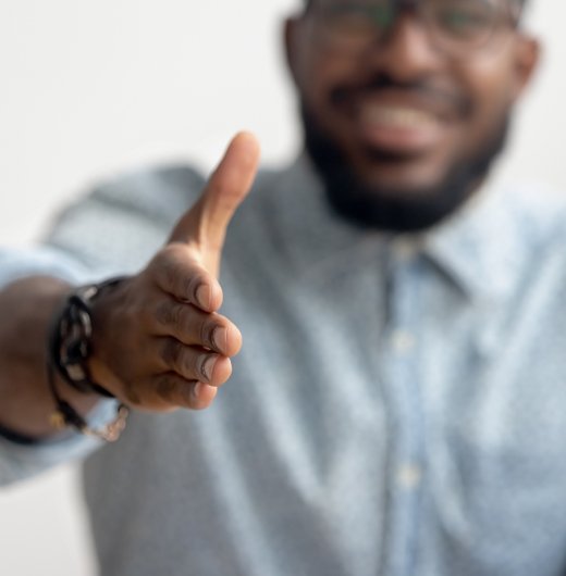 Direct Hire and Interim Placement Image a Black man in professional attire extends his hand for a handshake