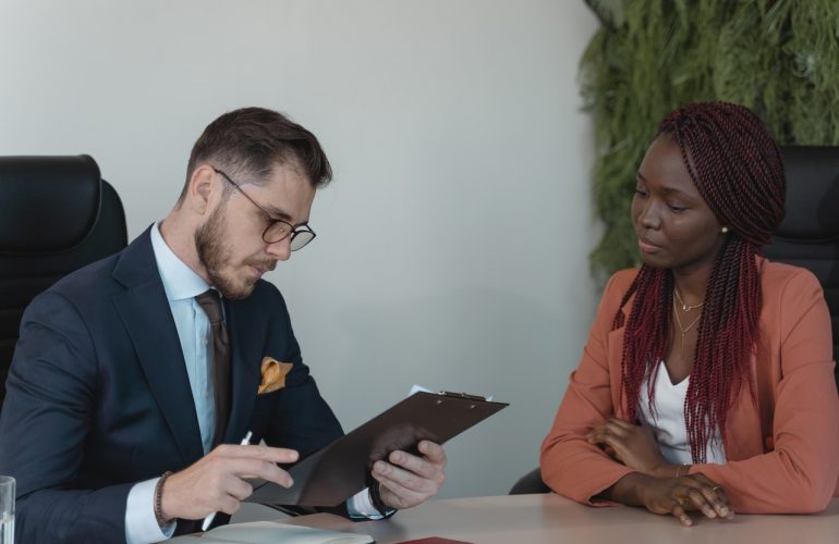 man looking at clipboard talking to woman