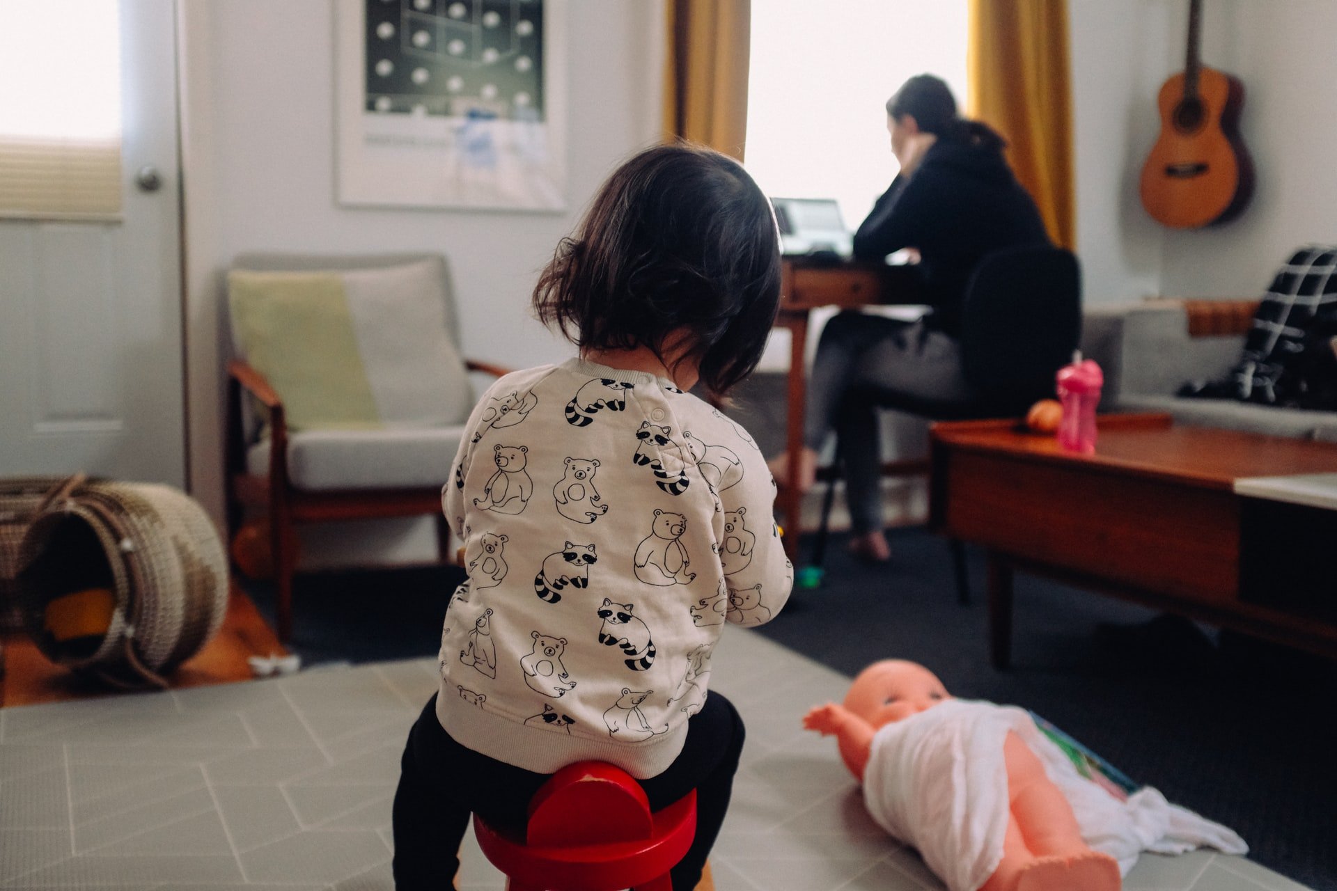 Child playing while parent works on computer in background