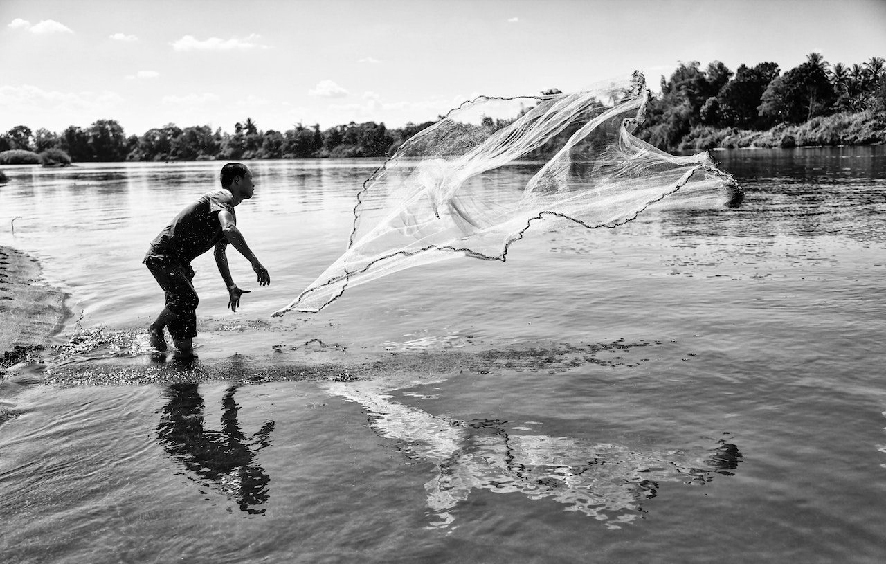 Man throwing fishing net on beach